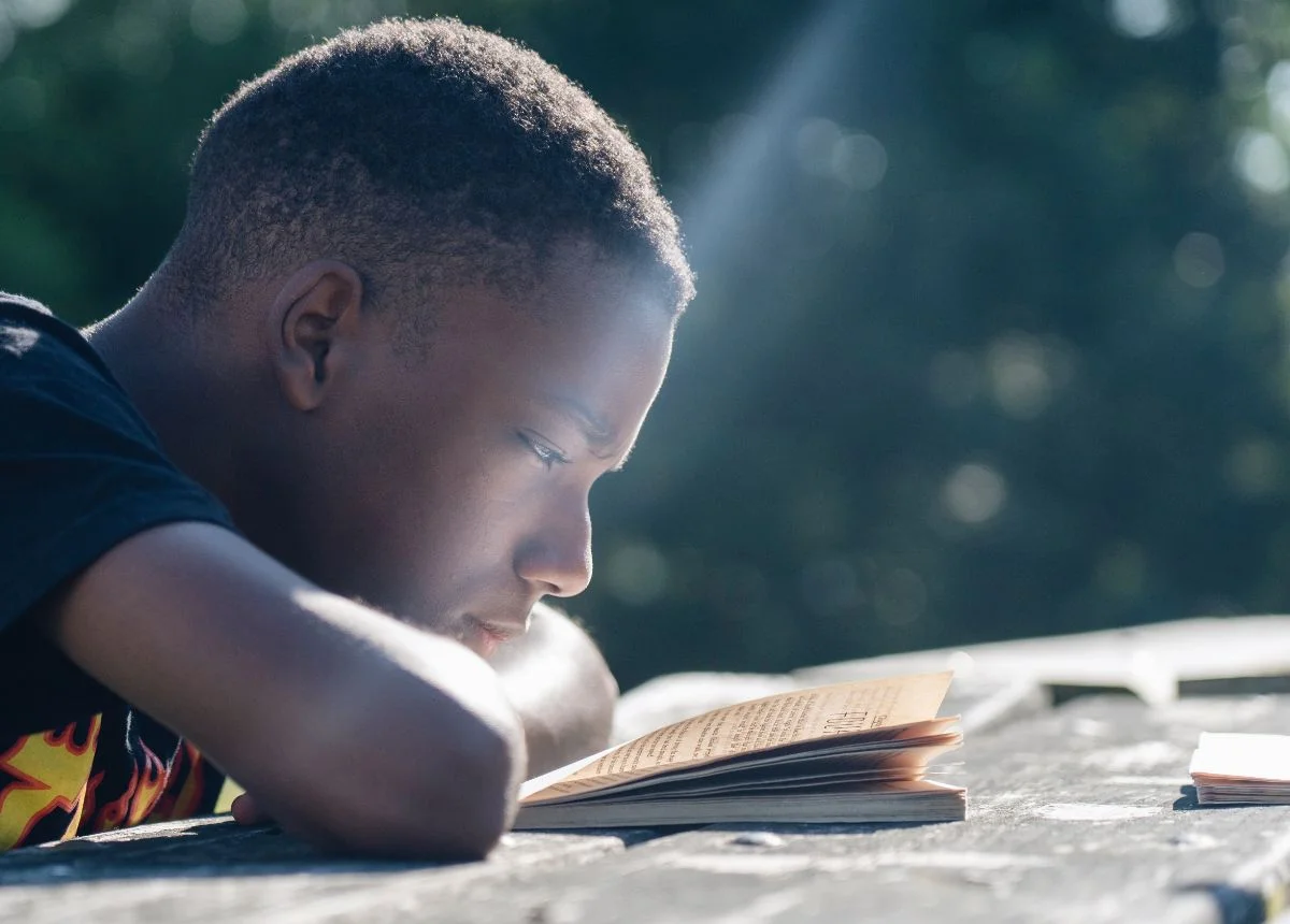 boy reading at table outside