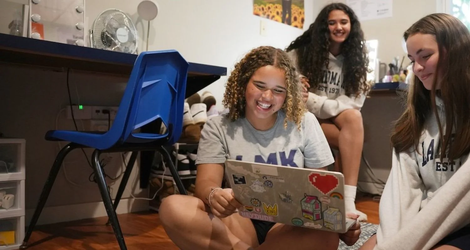 girls laughing together while working in dorm room