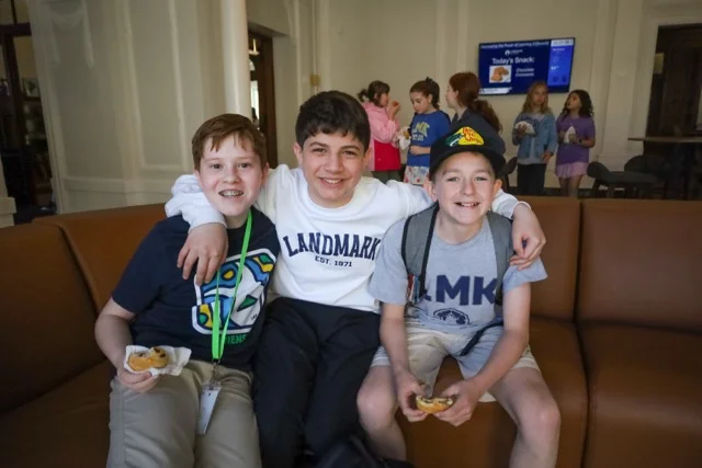 middle school boys sitting on couch with arms around each other