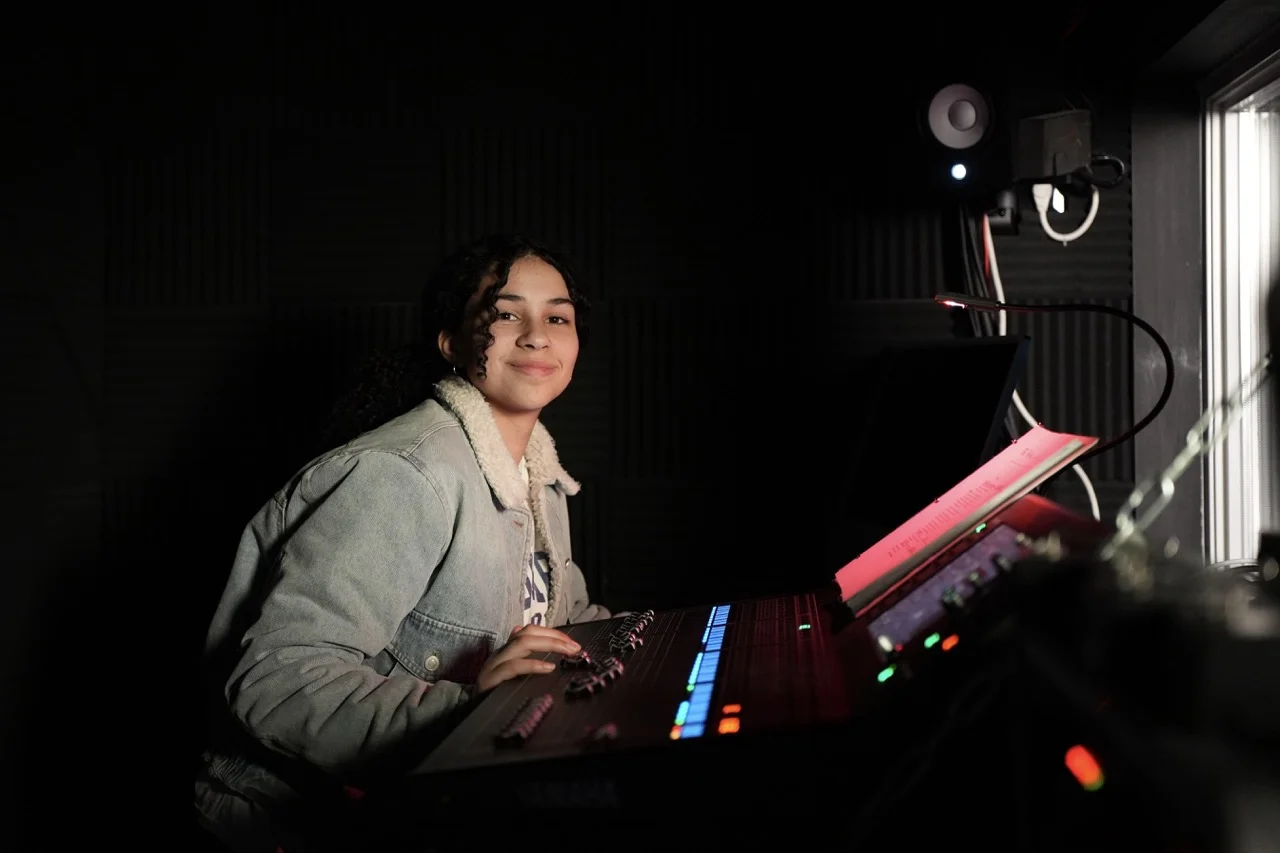 girl at sound board in theater tech studio