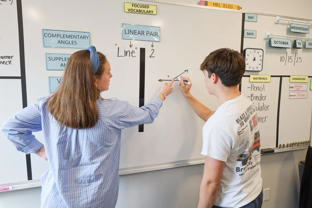 teacher giving explicit instructions on whiteboard with student and new breaking word into parts