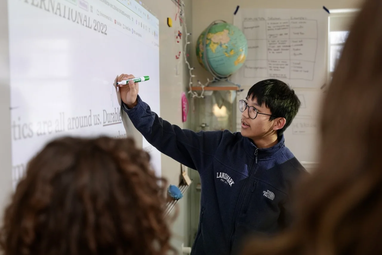 high school boy working at board with small class of students