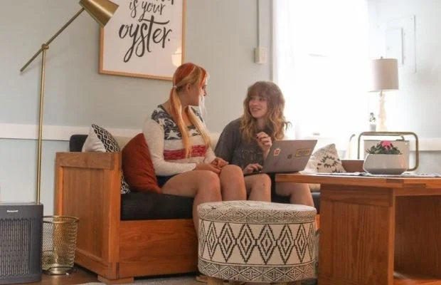 2 students using a laptop in a common room