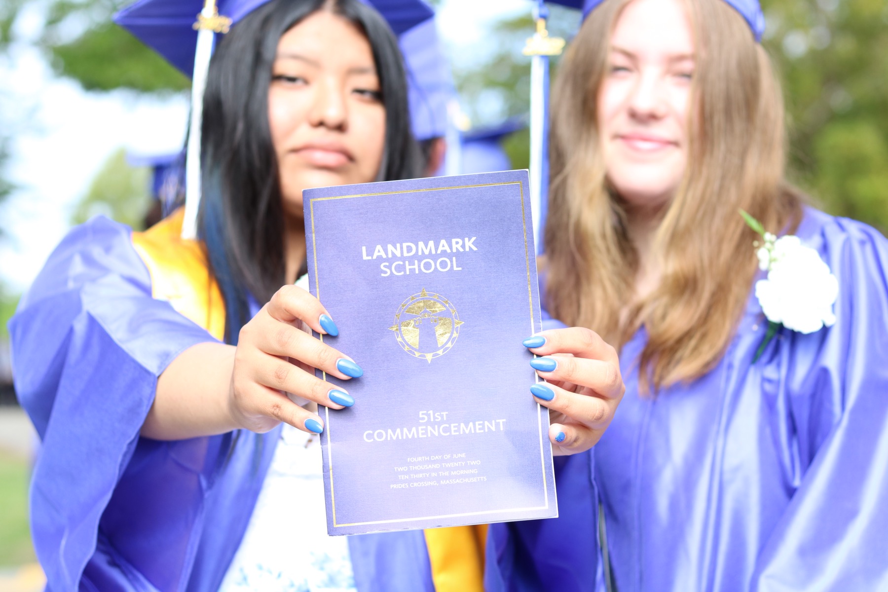 students at graduation holding program