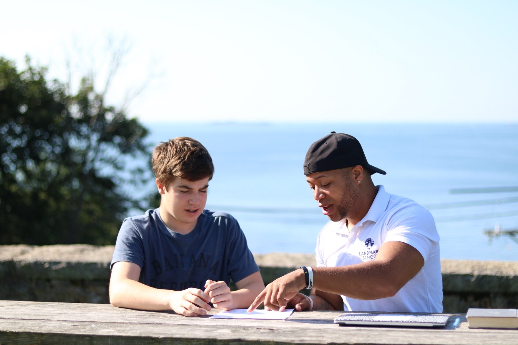 teacher working with student one on one for literacy and reading skills by ocean