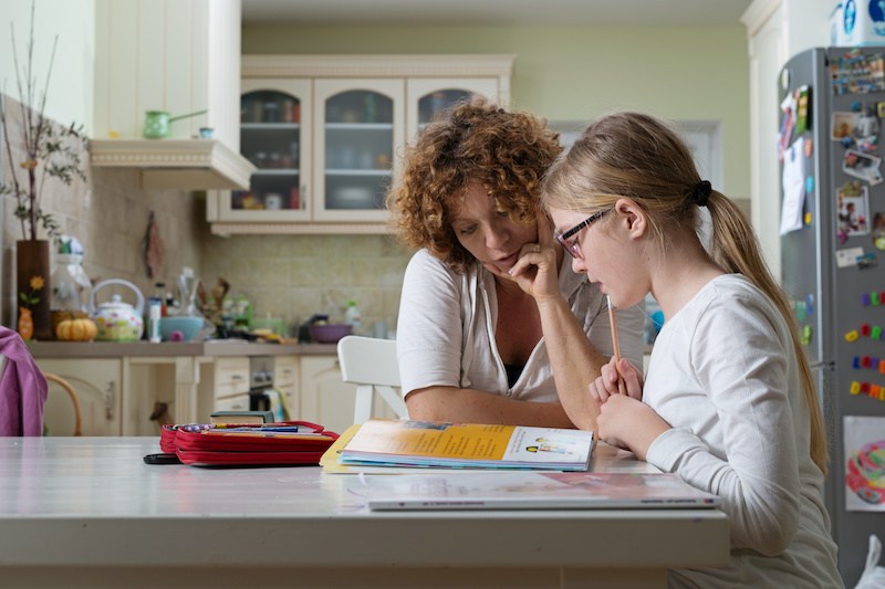 parent and child doing homework at table.