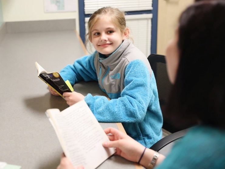girl reading at desk with teacher