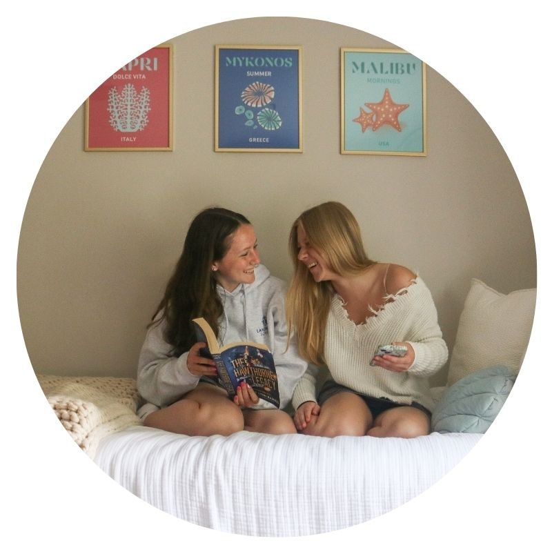Roommates laughing together with book